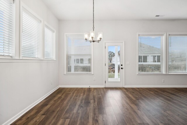 unfurnished dining area featuring plenty of natural light, dark hardwood / wood-style floors, and a notable chandelier