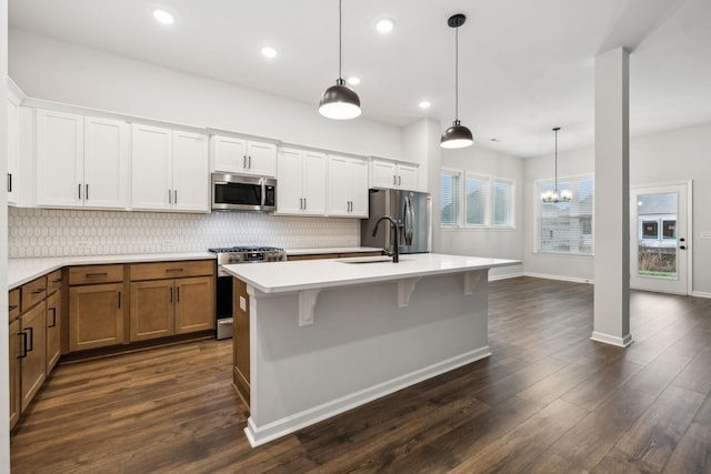 kitchen with white cabinetry, appliances with stainless steel finishes, a center island with sink, and pendant lighting