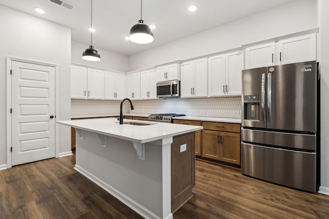 kitchen with sink, decorative light fixtures, a center island with sink, stainless steel appliances, and white cabinets