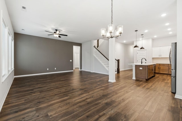 unfurnished living room with ceiling fan with notable chandelier, sink, and dark wood-type flooring