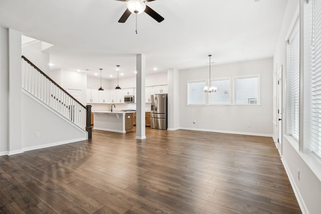 unfurnished living room with sink, dark hardwood / wood-style floors, and ceiling fan with notable chandelier