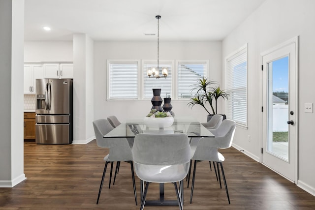 dining area with a notable chandelier and dark hardwood / wood-style flooring