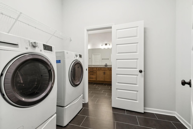 washroom featuring sink, washer and clothes dryer, and dark tile patterned floors