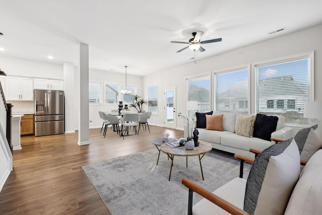 living room with wood-type flooring and ceiling fan with notable chandelier