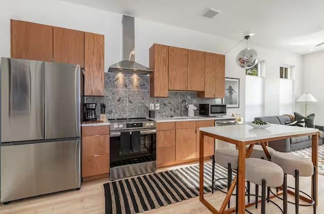 kitchen with wall chimney exhaust hood, appliances with stainless steel finishes, sink, and backsplash