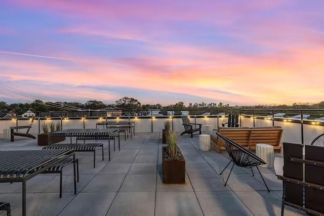 patio terrace at dusk featuring a water view