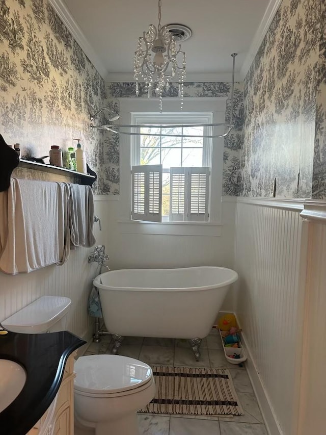 bathroom featuring toilet, ornamental molding, vanity, a bathing tub, and a notable chandelier