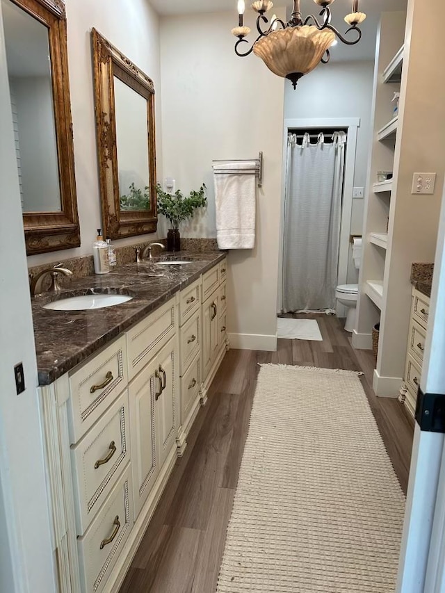 bathroom with hardwood / wood-style flooring, vanity, an inviting chandelier, and toilet