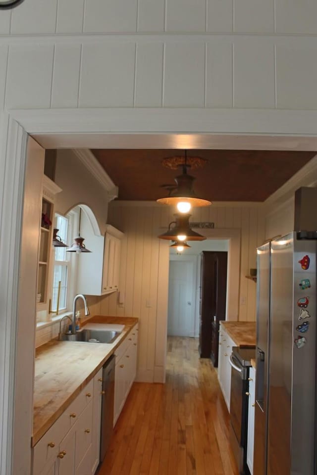 kitchen featuring sink, white cabinetry, stainless steel appliances, light hardwood / wood-style floors, and wood counters