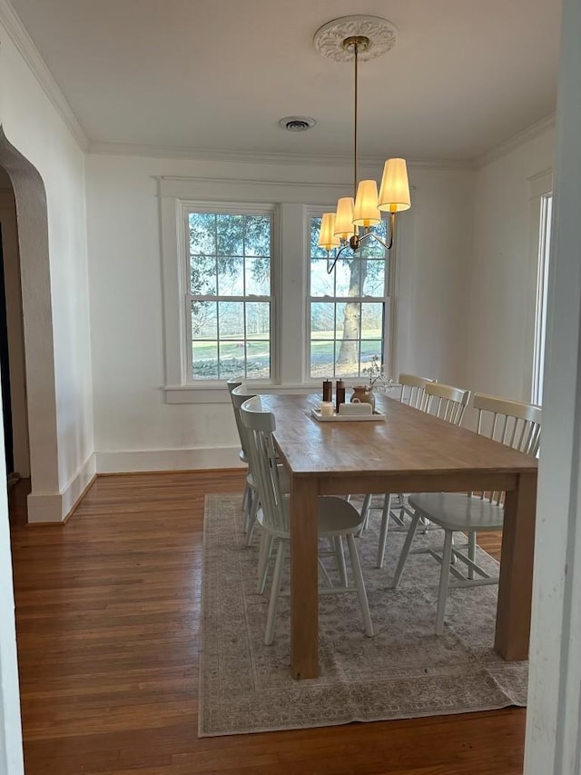 unfurnished dining area with a notable chandelier, dark wood-type flooring, and ornamental molding