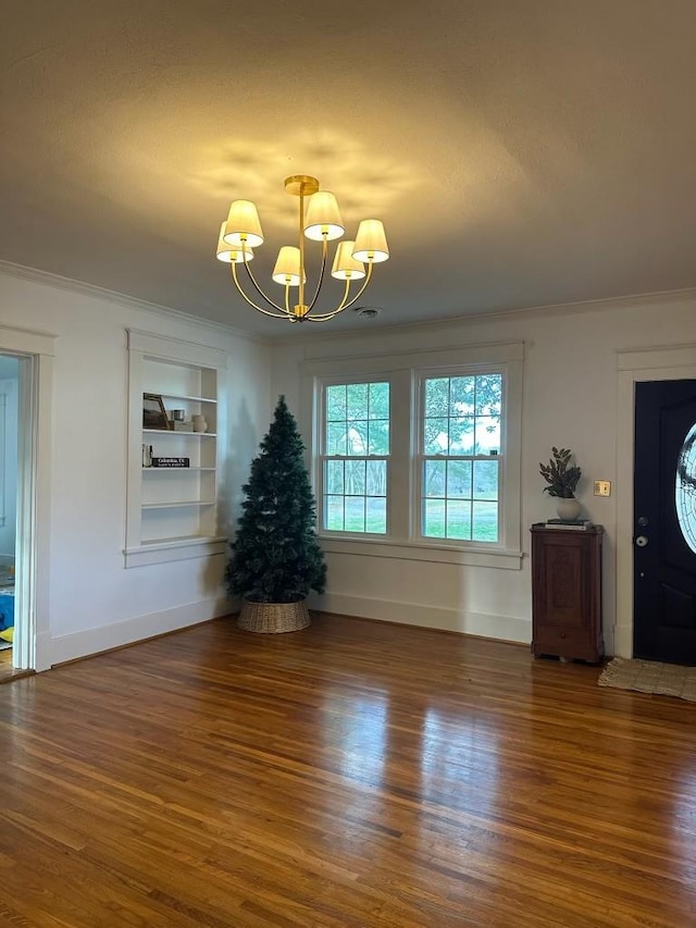 entrance foyer featuring ornamental molding, dark hardwood / wood-style floors, and an inviting chandelier