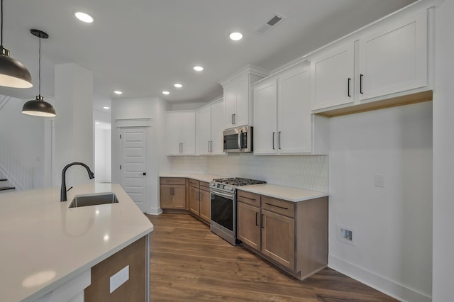 kitchen featuring pendant lighting, sink, appliances with stainless steel finishes, backsplash, and white cabinets