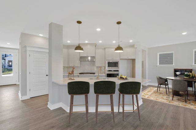 kitchen with stainless steel appliances, sink, a kitchen bar, and decorative light fixtures