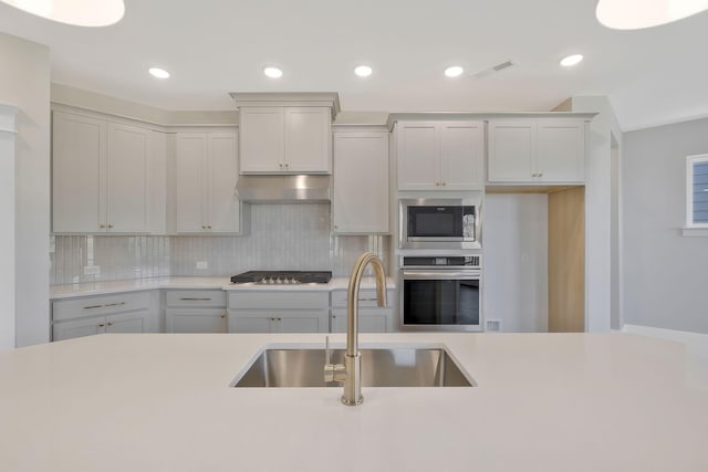 kitchen with tasteful backsplash, sink, and appliances with stainless steel finishes