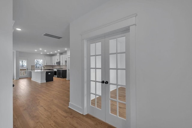 hall featuring sink, hardwood / wood-style flooring, and french doors