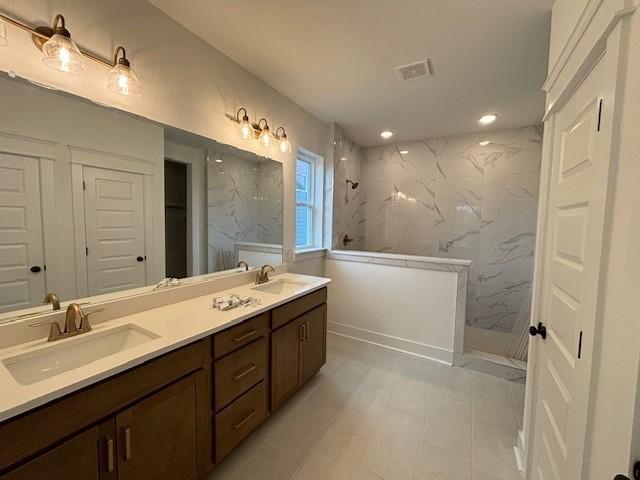 bathroom with vanity and tiled shower