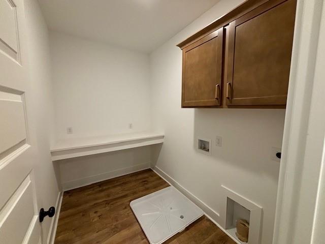 laundry area with washer hookup, dark wood-type flooring, and cabinets