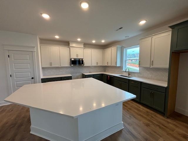 kitchen featuring a center island, sink, white cabinets, and dark wood-type flooring