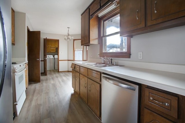 kitchen with sink, separate washer and dryer, hanging light fixtures, light hardwood / wood-style flooring, and stainless steel appliances