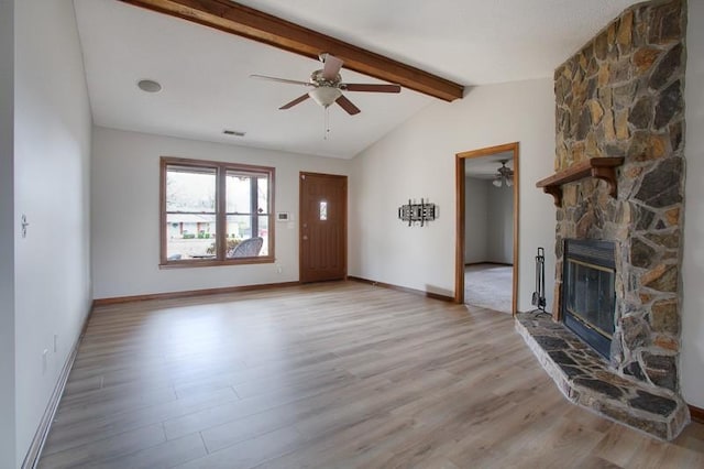 unfurnished living room with ceiling fan, a stone fireplace, light hardwood / wood-style floors, and lofted ceiling with beams