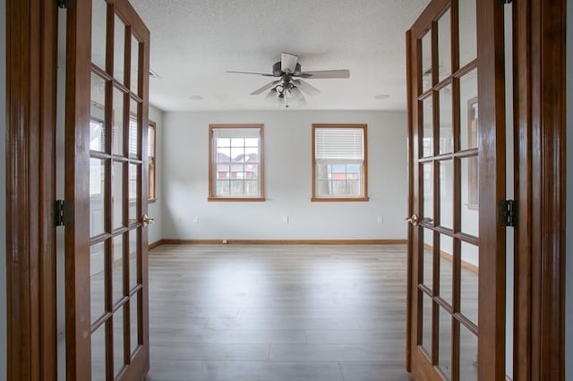 spare room featuring light hardwood / wood-style flooring, ceiling fan, and french doors