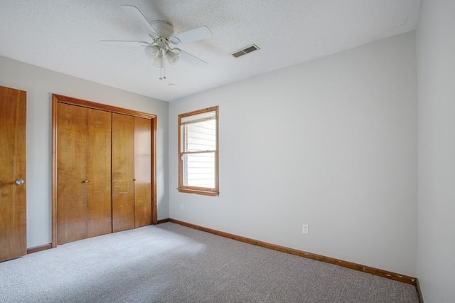 unfurnished bedroom with ceiling fan, carpet floors, a textured ceiling, and a closet