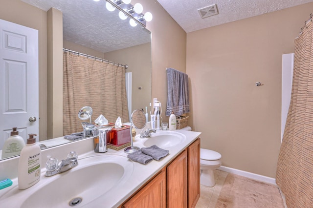 bathroom with tile patterned floors, vanity, toilet, and a textured ceiling