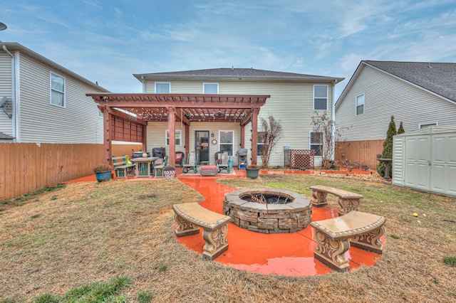 back of property featuring a storage shed, a fire pit, a pergola, a yard, and a patio