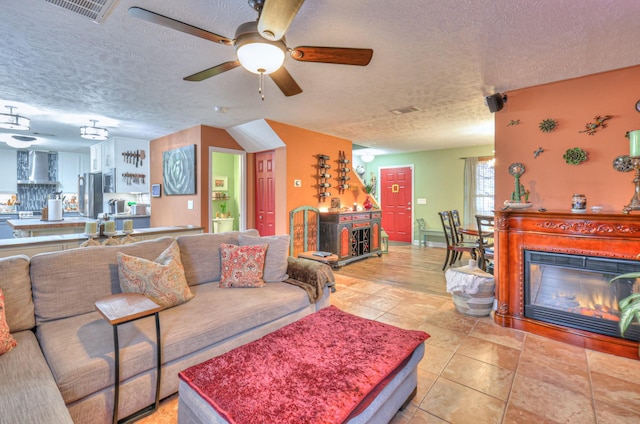 living room featuring ceiling fan, a textured ceiling, and light tile patterned flooring