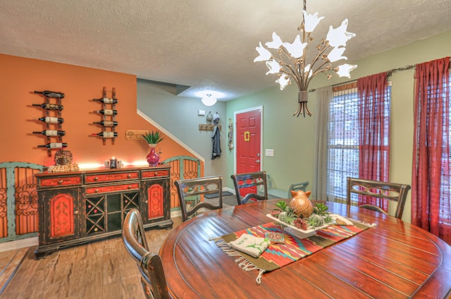 dining area featuring hardwood / wood-style flooring, a chandelier, and a textured ceiling