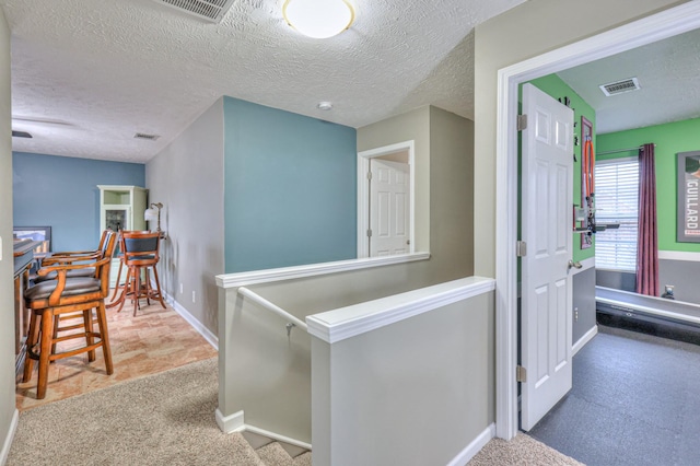 hallway with carpet floors and a textured ceiling