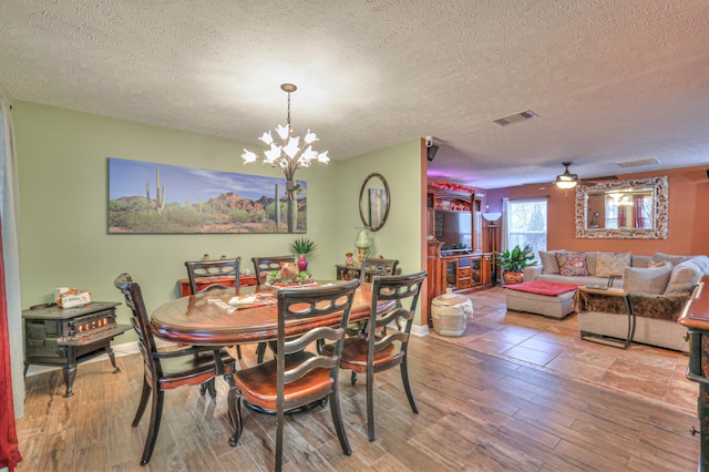 dining room featuring hardwood / wood-style flooring, ceiling fan with notable chandelier, and a textured ceiling