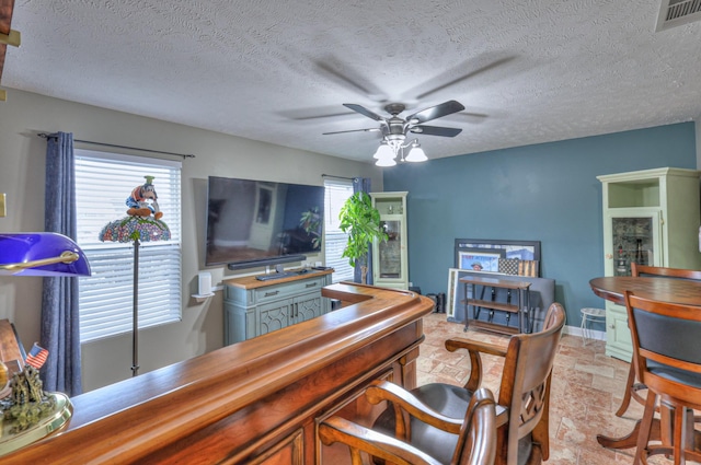 home office featuring ceiling fan and a textured ceiling