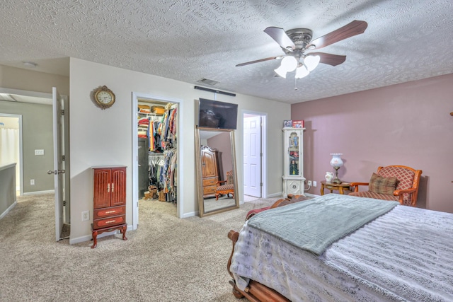 bedroom with a spacious closet, light carpet, a textured ceiling, and a closet