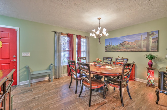 dining area featuring hardwood / wood-style floors, a notable chandelier, and a textured ceiling