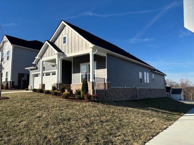 view of side of home featuring a garage, a yard, and covered porch