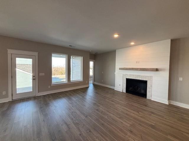 unfurnished living room featuring dark hardwood / wood-style floors and a tile fireplace