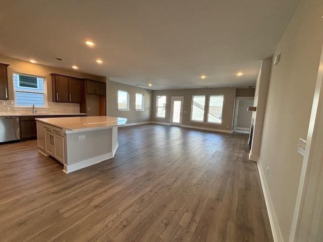 kitchen featuring dark hardwood / wood-style floors, tasteful backsplash, dark brown cabinetry, a kitchen island, and stainless steel dishwasher