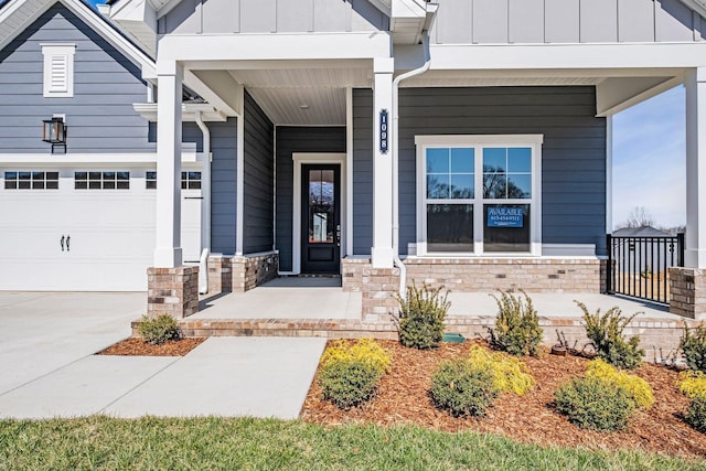 doorway to property featuring covered porch, board and batten siding, driveway, and a garage