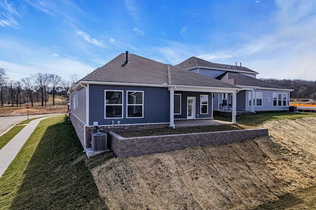 view of front of house with a front lawn, central AC, and a shingled roof