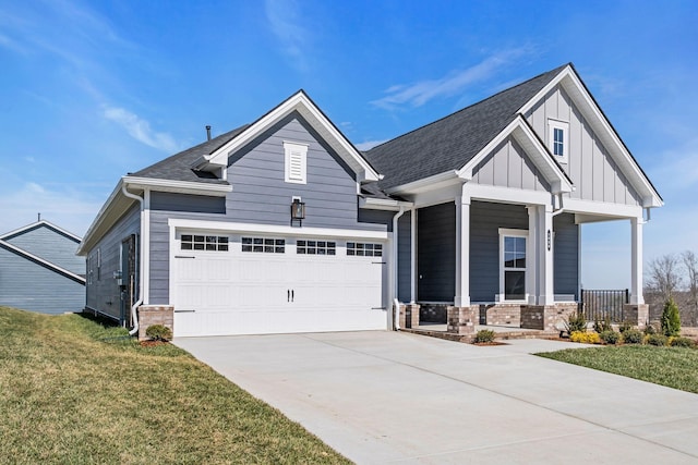 view of front of property featuring a front yard, driveway, a porch, an attached garage, and board and batten siding