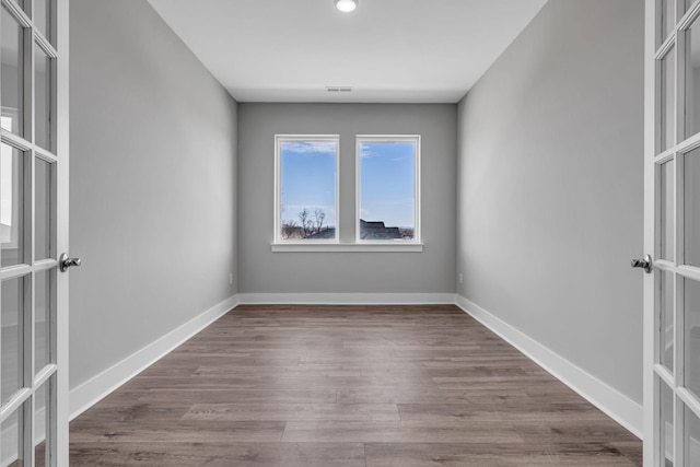 spare room with visible vents, baseboards, and wood finished floors