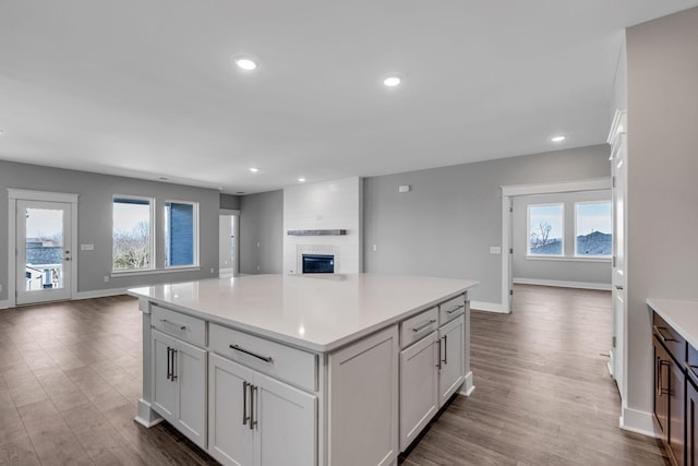 kitchen with recessed lighting, light countertops, dark wood-type flooring, open floor plan, and a large fireplace