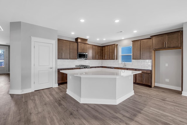 kitchen featuring stainless steel microwave, plenty of natural light, wood finished floors, and a center island