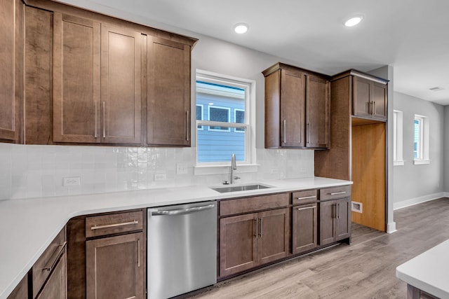 kitchen with a sink, tasteful backsplash, stainless steel dishwasher, light wood-style floors, and light countertops