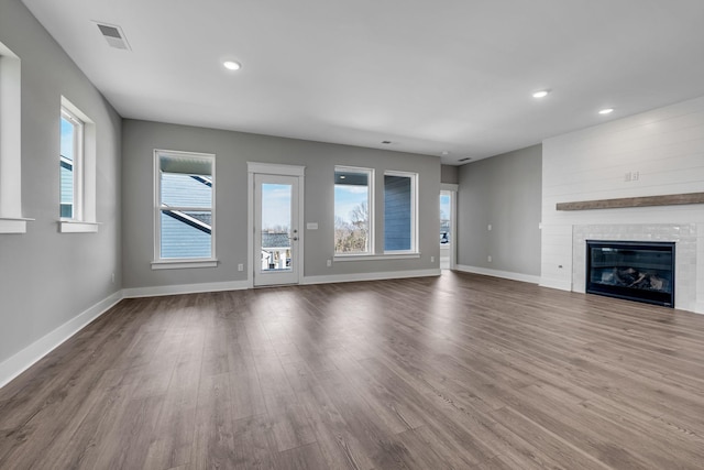 unfurnished living room with a fireplace, recessed lighting, wood finished floors, and baseboards