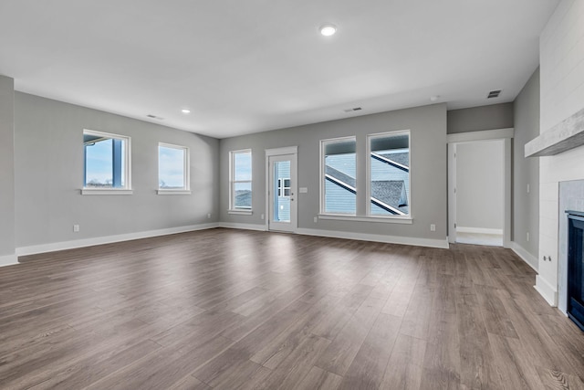 unfurnished living room with visible vents, baseboards, recessed lighting, a tile fireplace, and dark wood-style floors