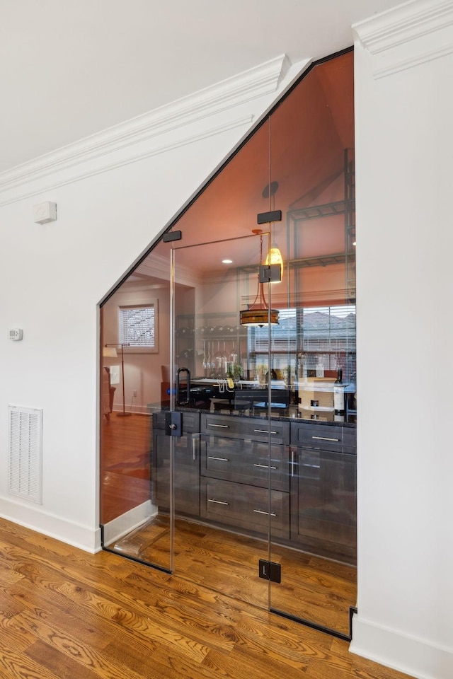 bar featuring wood-type flooring, sink, crown molding, and decorative light fixtures