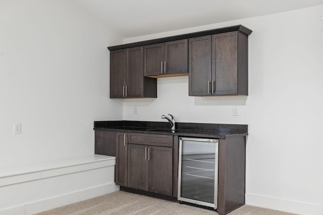 kitchen featuring dark brown cabinets, sink, light colored carpet, and wine cooler