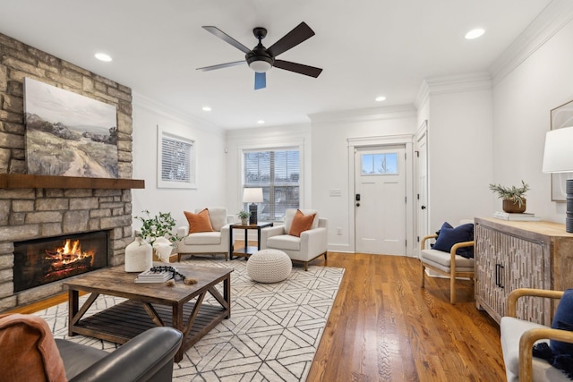 living room with light hardwood / wood-style flooring, a fireplace, ornamental molding, and ceiling fan